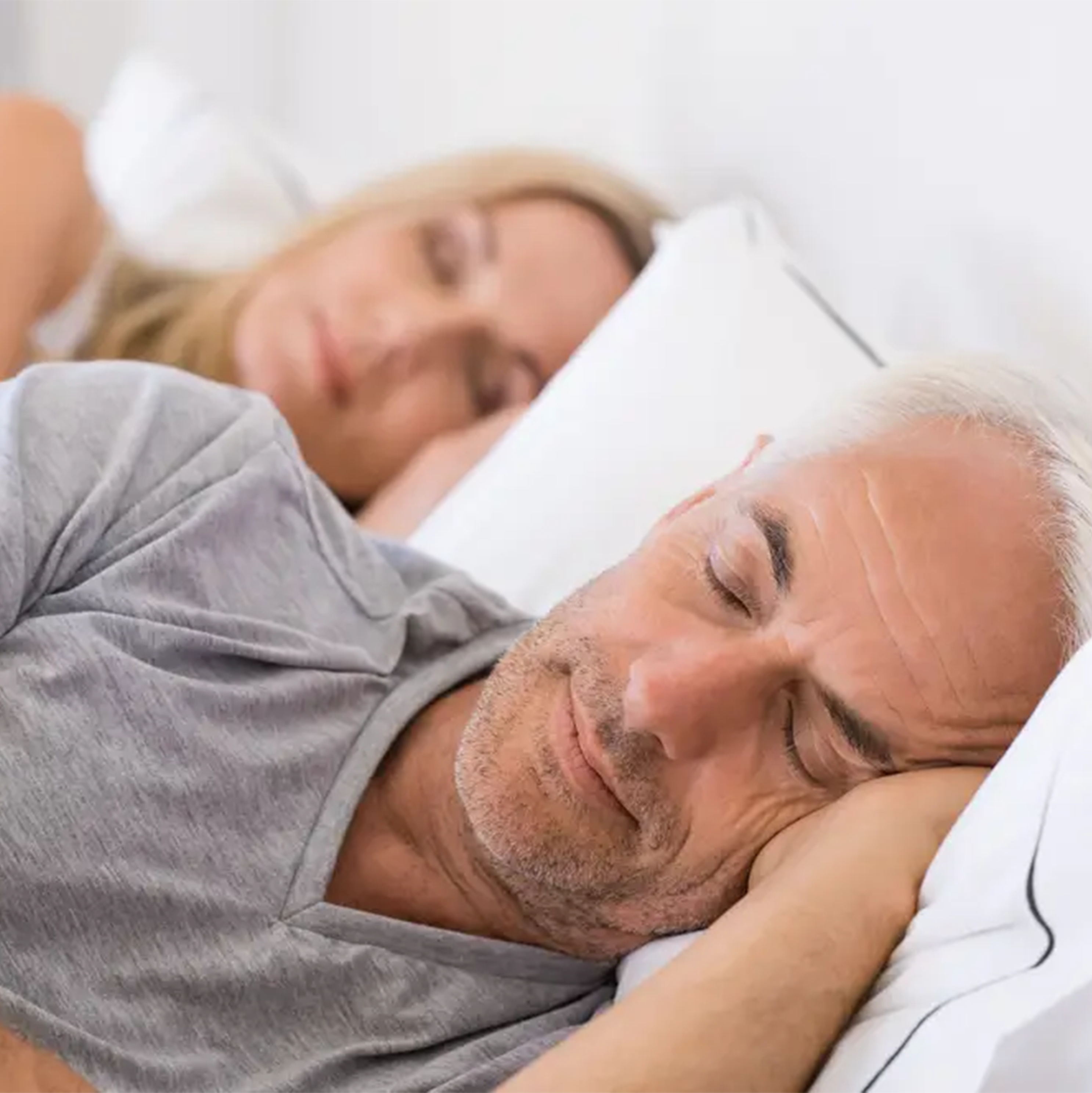 Older couple sleeping peacefully in bed after successful cognitive behavioral therapy for insomnia treatment.